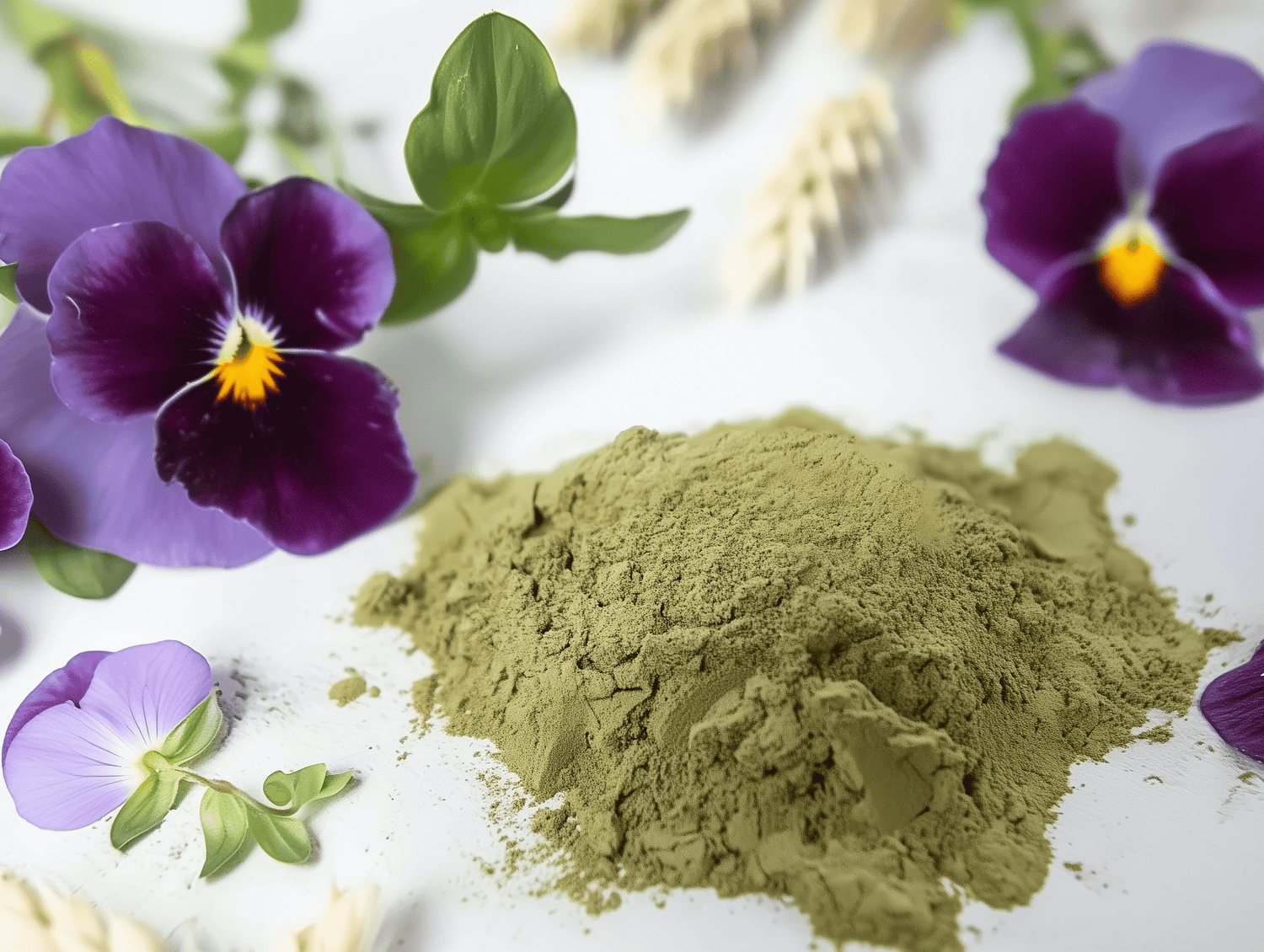 Ein kleiner Haufen von unserem grünen, pulverförmigen Badezusatz platziert auf einem weißen Tisch und von Blumen umgeben.